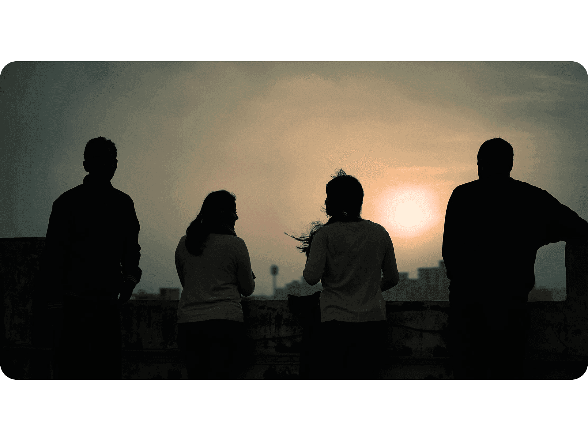 Vier Personen von hinten schauen sich den Sonnenaufgang an